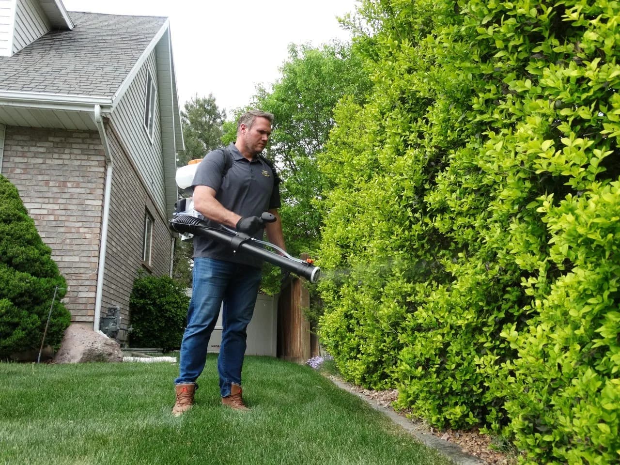Reynolds technician treating the exterior of a landscaped home